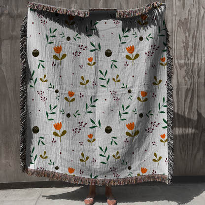 Modern boho floral woven throw blanket with fringe in orange and green botanical design
